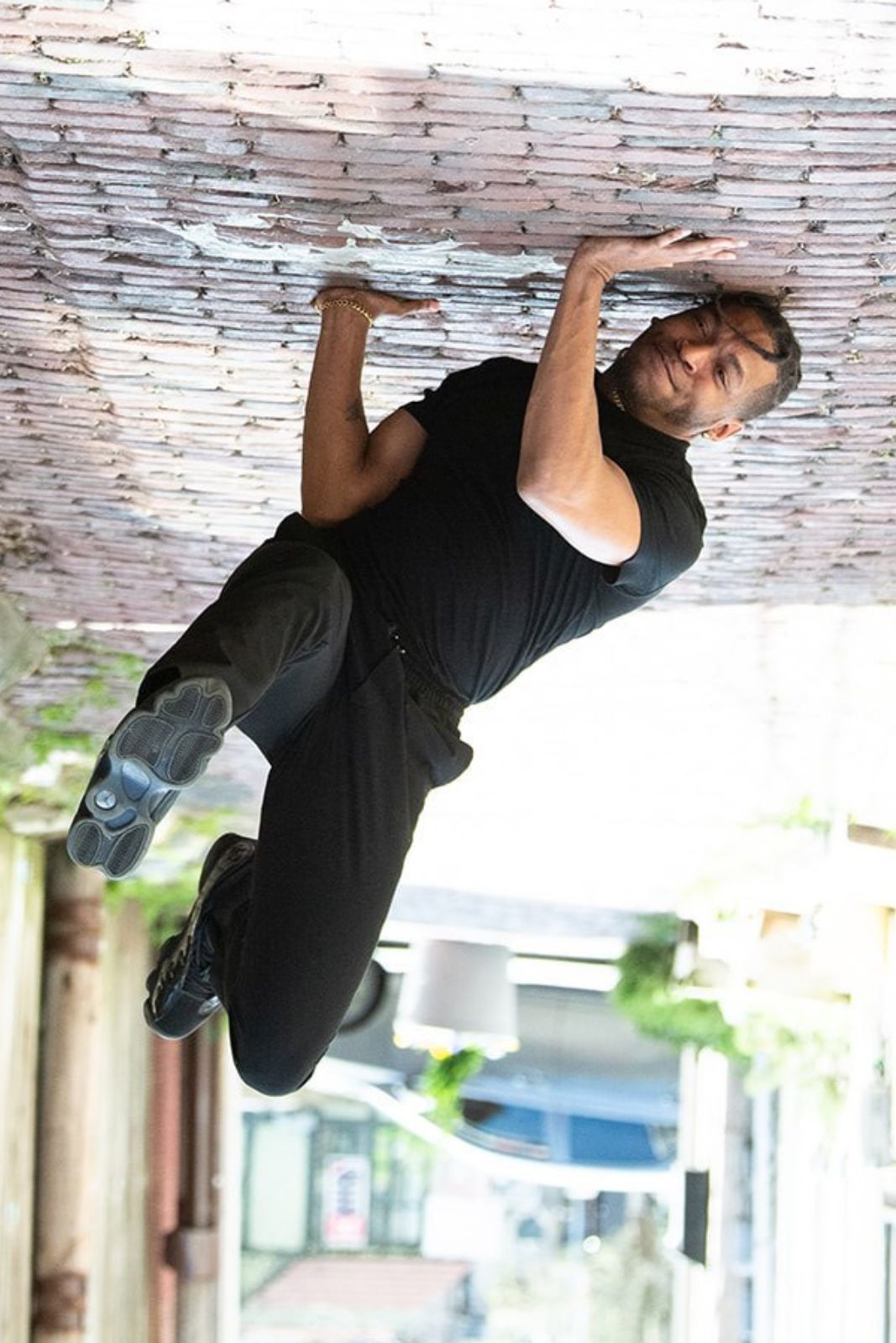 A man is standing upside down on a brick sidewalk.