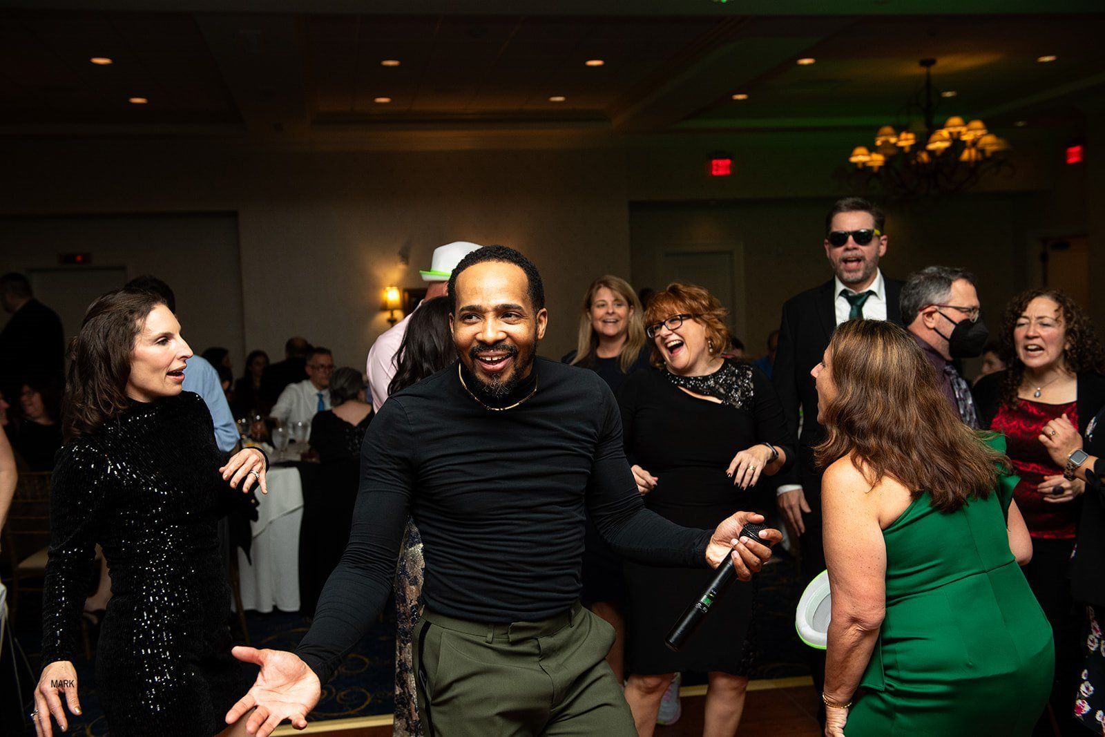 A group of people dancing and laughing together at an indoor social event.