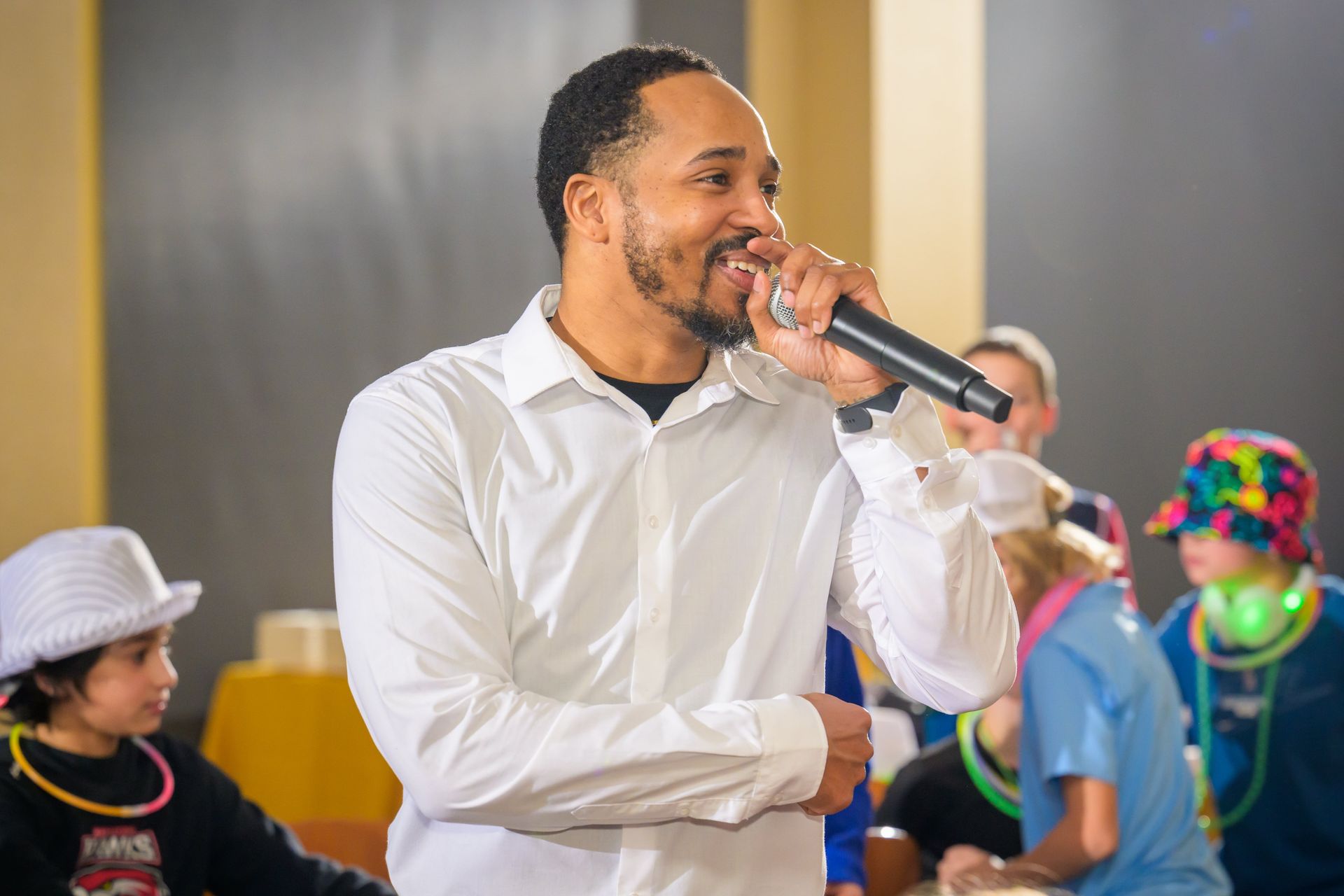 A man in a white button-down shirt speaks into a microphone.