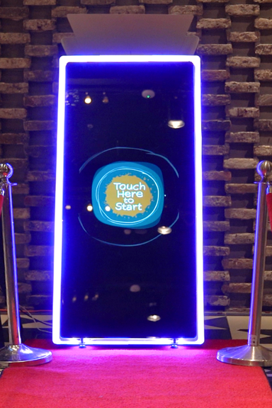 Mirror booth setup with LED lighting and red carpet entrance at an event venue.