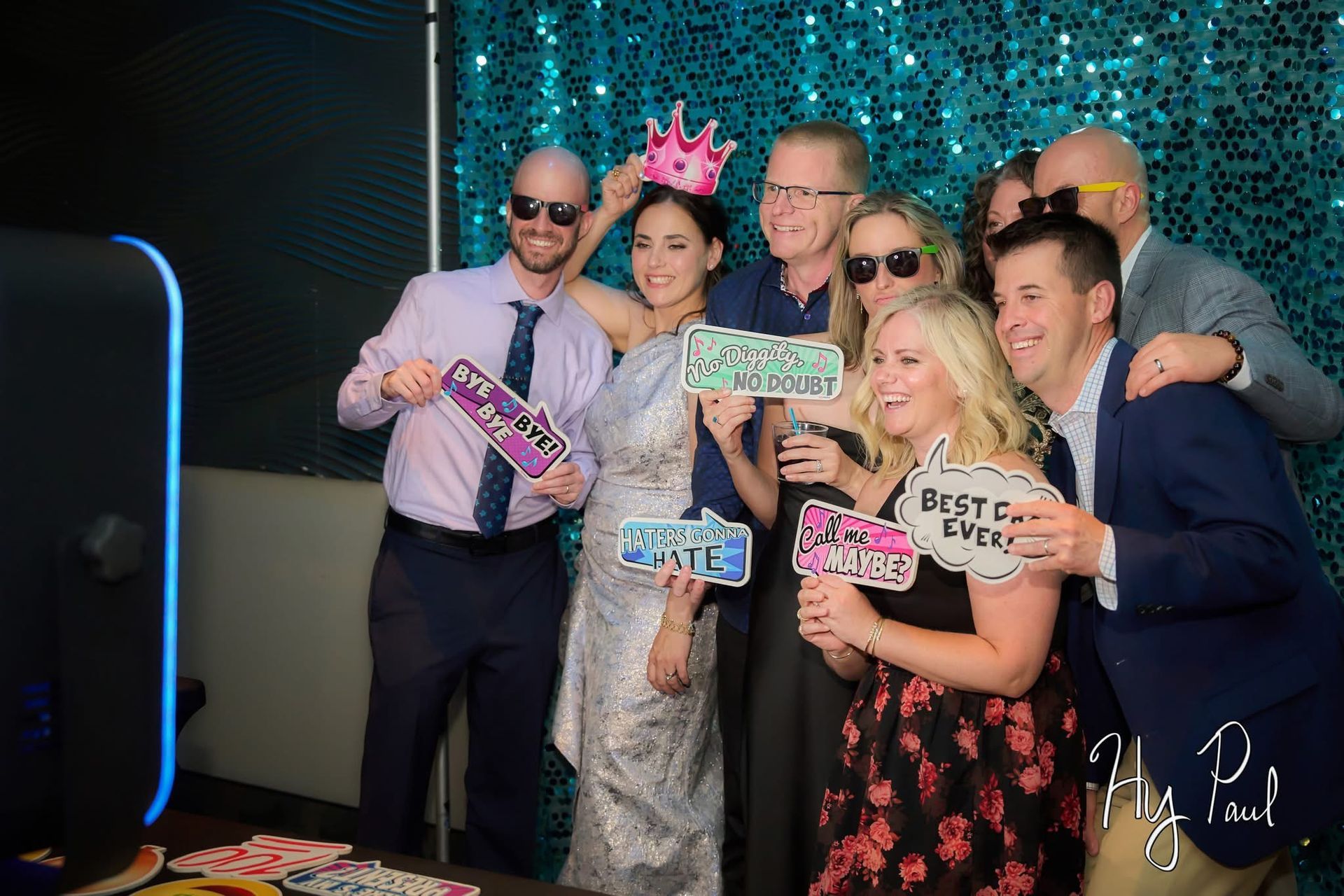 People posing with fun props in an open air photo booth, smiling and enjoying the lively atmosphere.