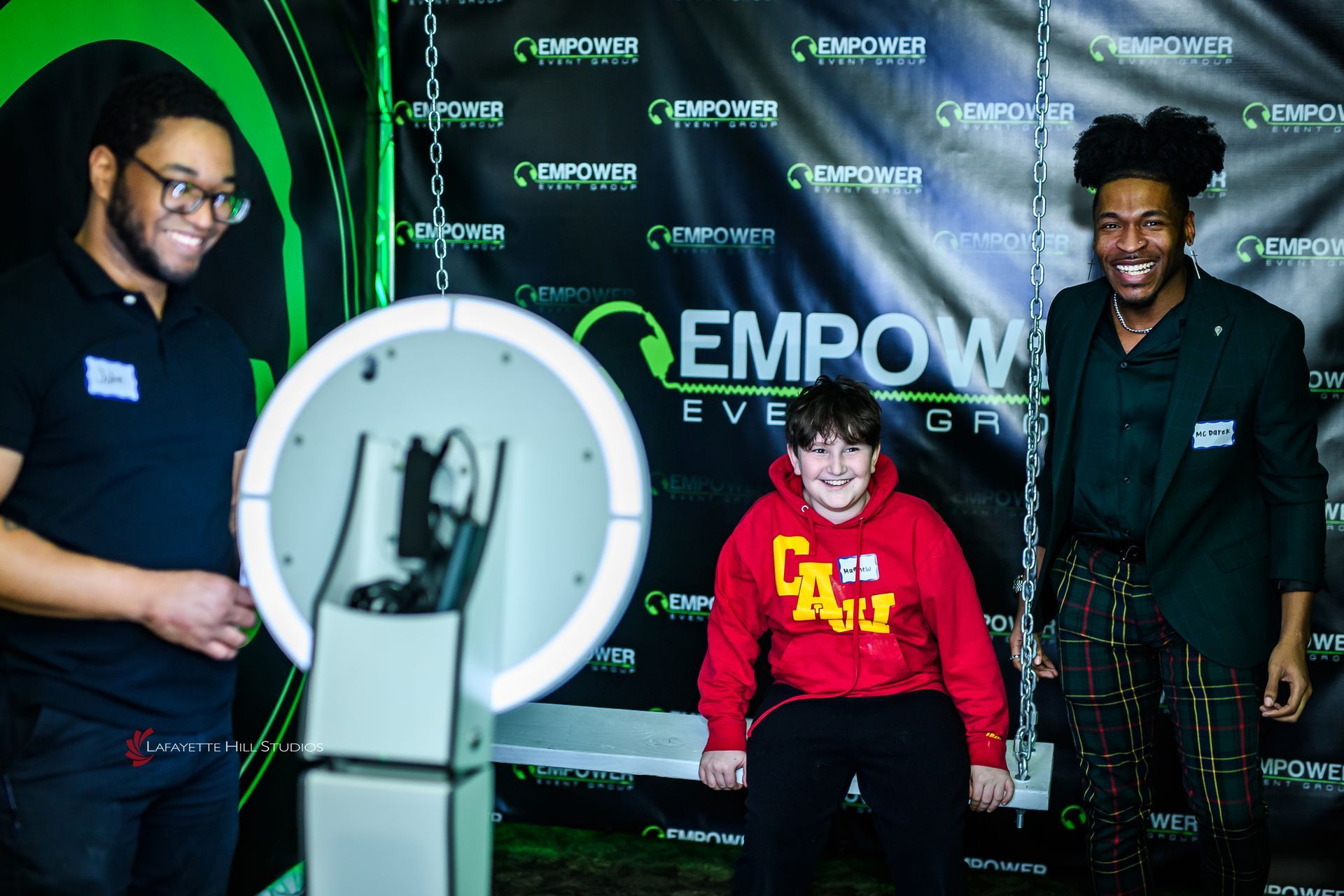 Professional team members seated together, smiling confidently in front of branded backdrop, ready for event entertainment.