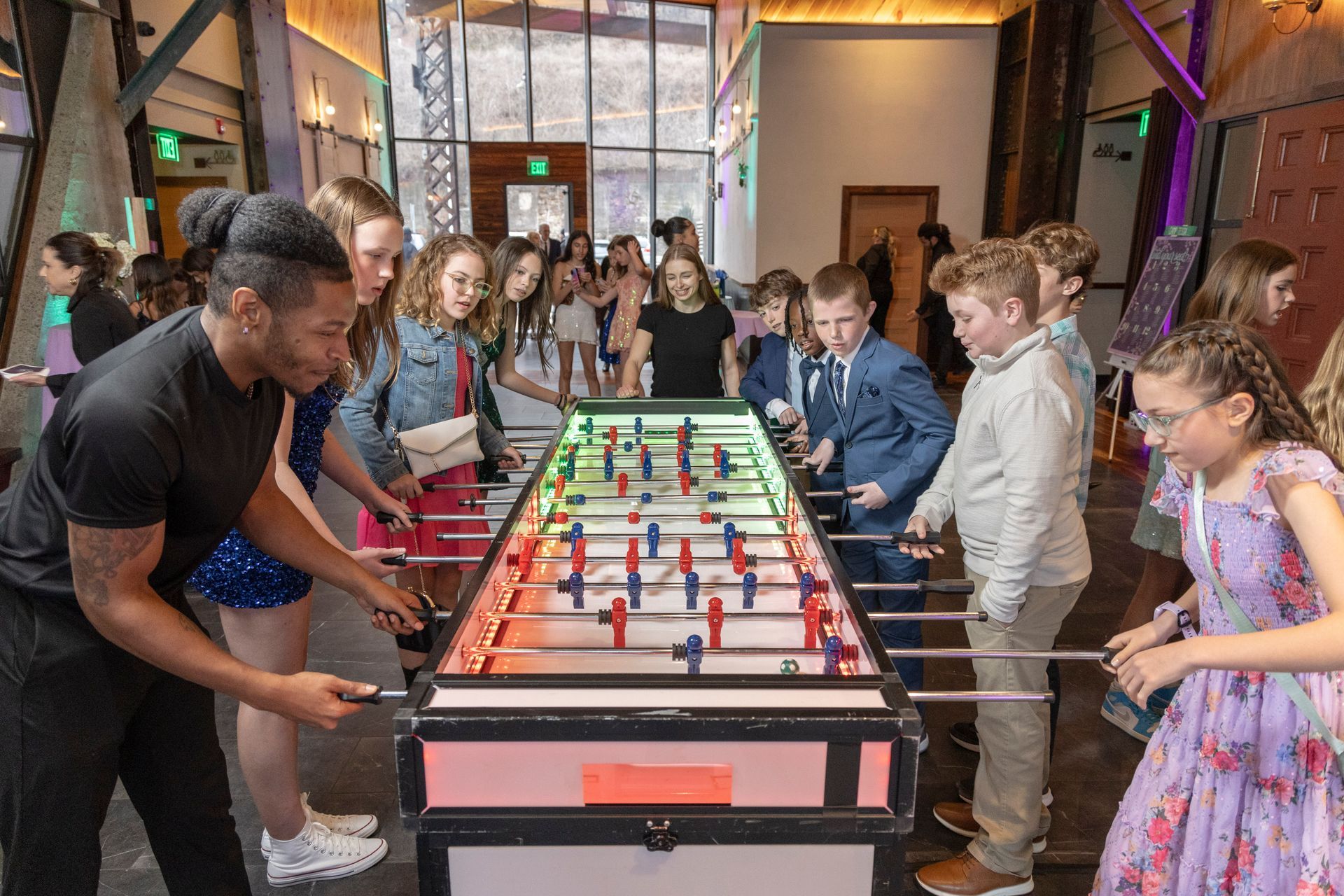 People playing foosball at a long table in a busy indoor event space