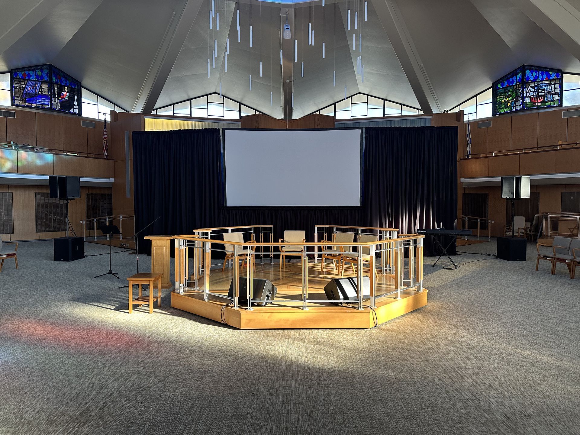 Conference stage with projection screen, podium and microphones.