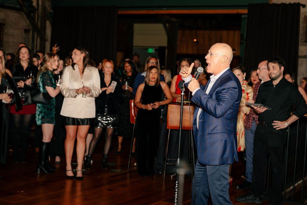 Company leader giving remarks on a wireless mic at a holiday party.