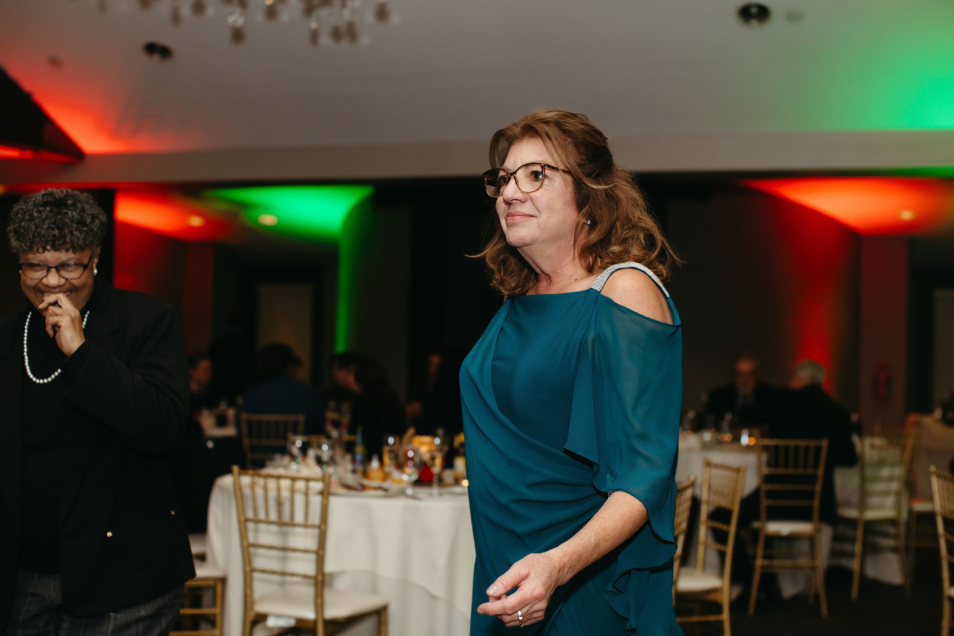 Wedding guests dancing in a room washed with red and green uplighting