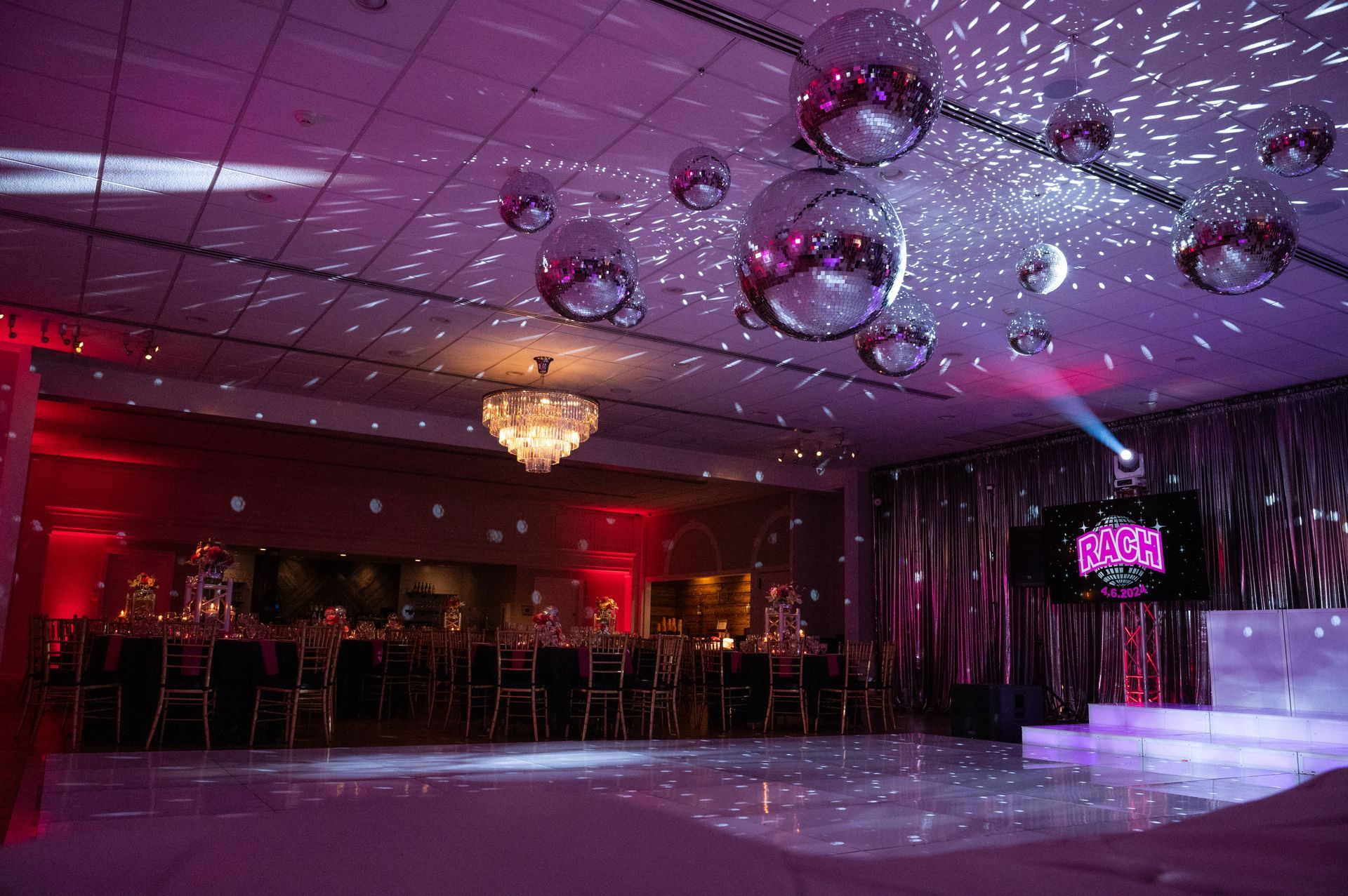 Empty banquet hall with purple lighting, disco balls, and a small stage with steps