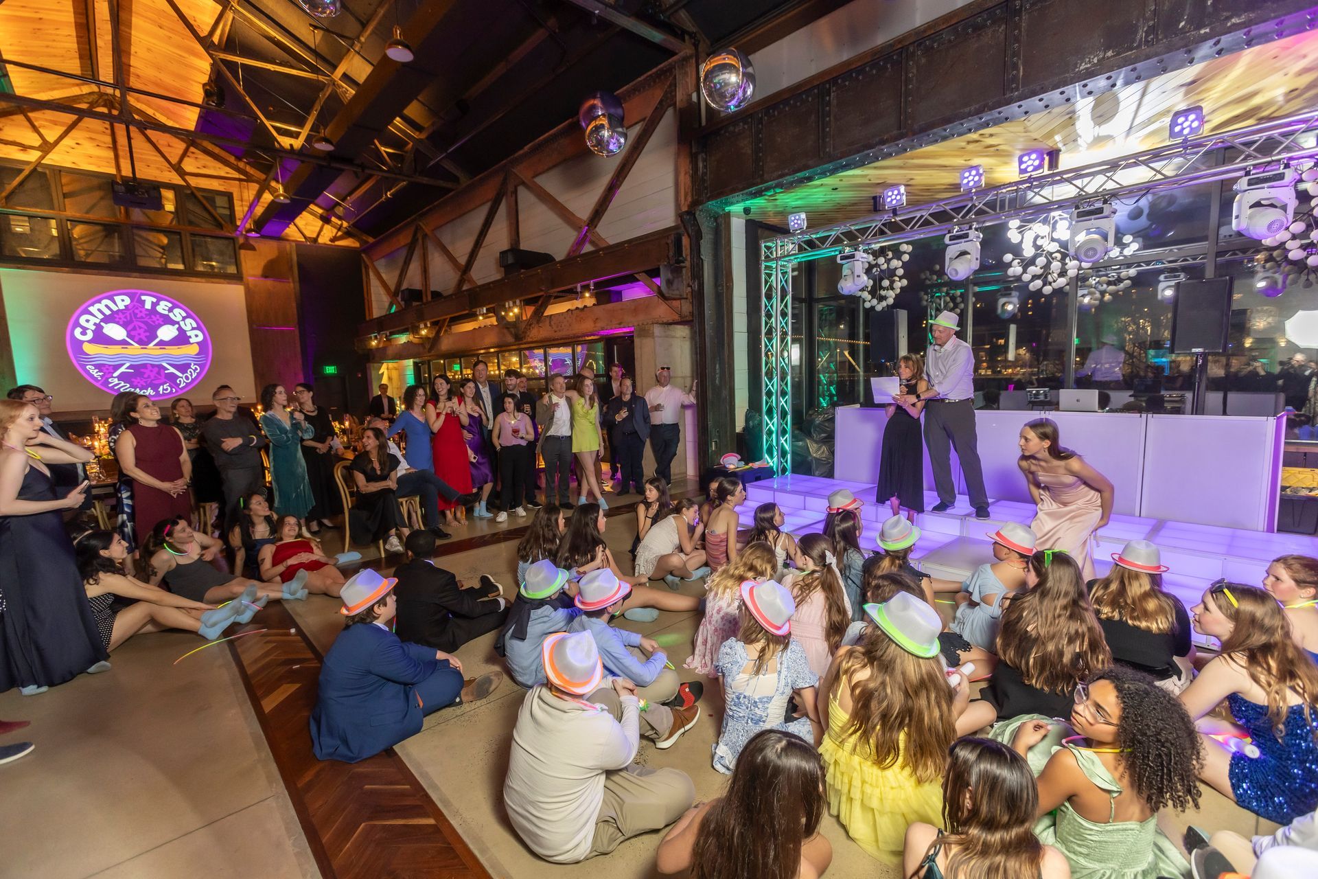 Lit stage with truss lighting, mirror balls and a custom camp-themed logo projected on the wall