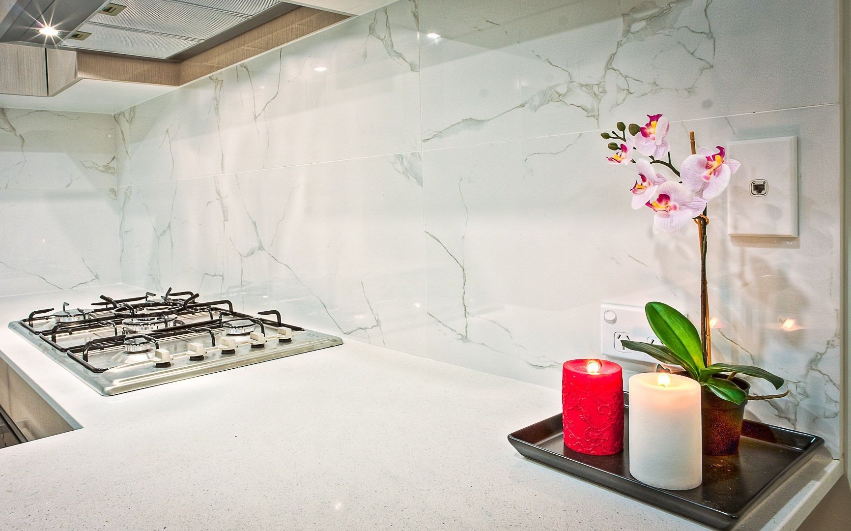 A kitchen counter with two candles and a flower on it