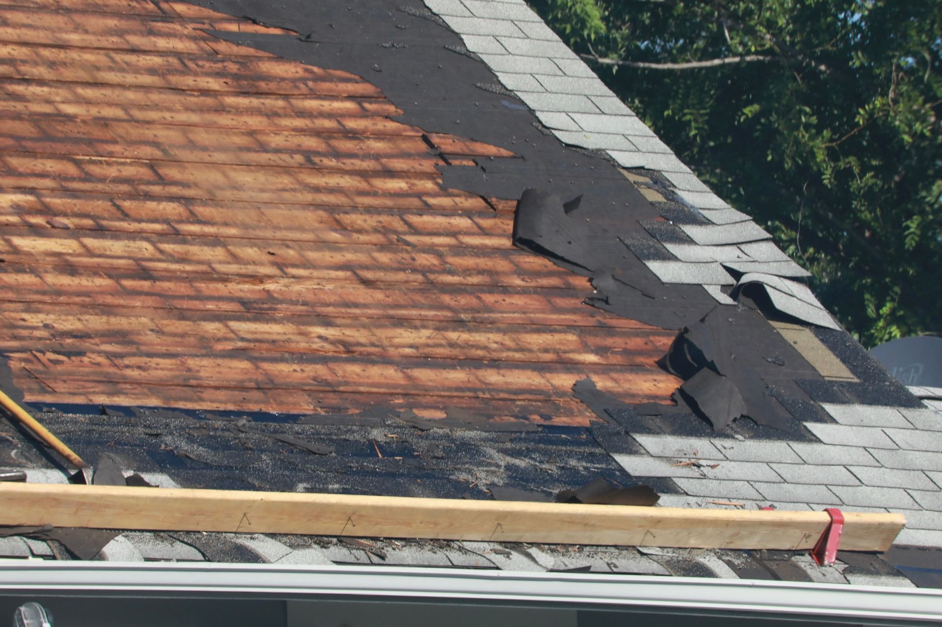 A roof is being repaired with shingles and a wooden beam