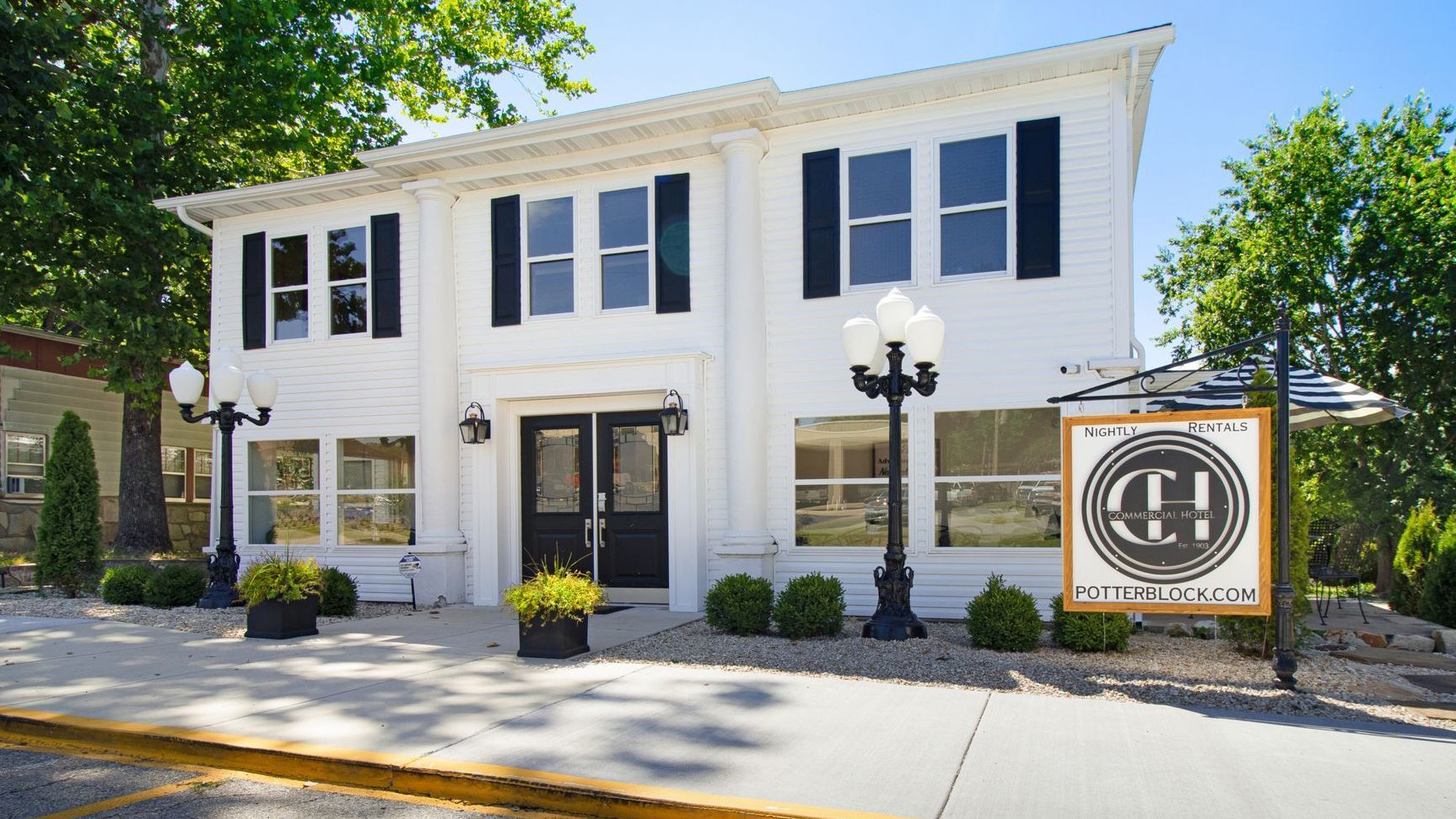 A white building with black shutters and a sign that says ch