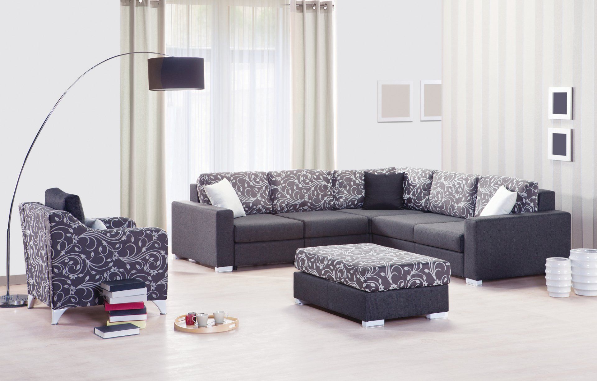 Decorative purple and white lounge suite, books and coffee cups on tray on floor, under overhanging lamp. Set in front of opaque sheers with fawn eyelet curtains pulled to the sides.