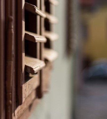 Close up view of timber Plantation Shutters in foreground with blurred background wall.