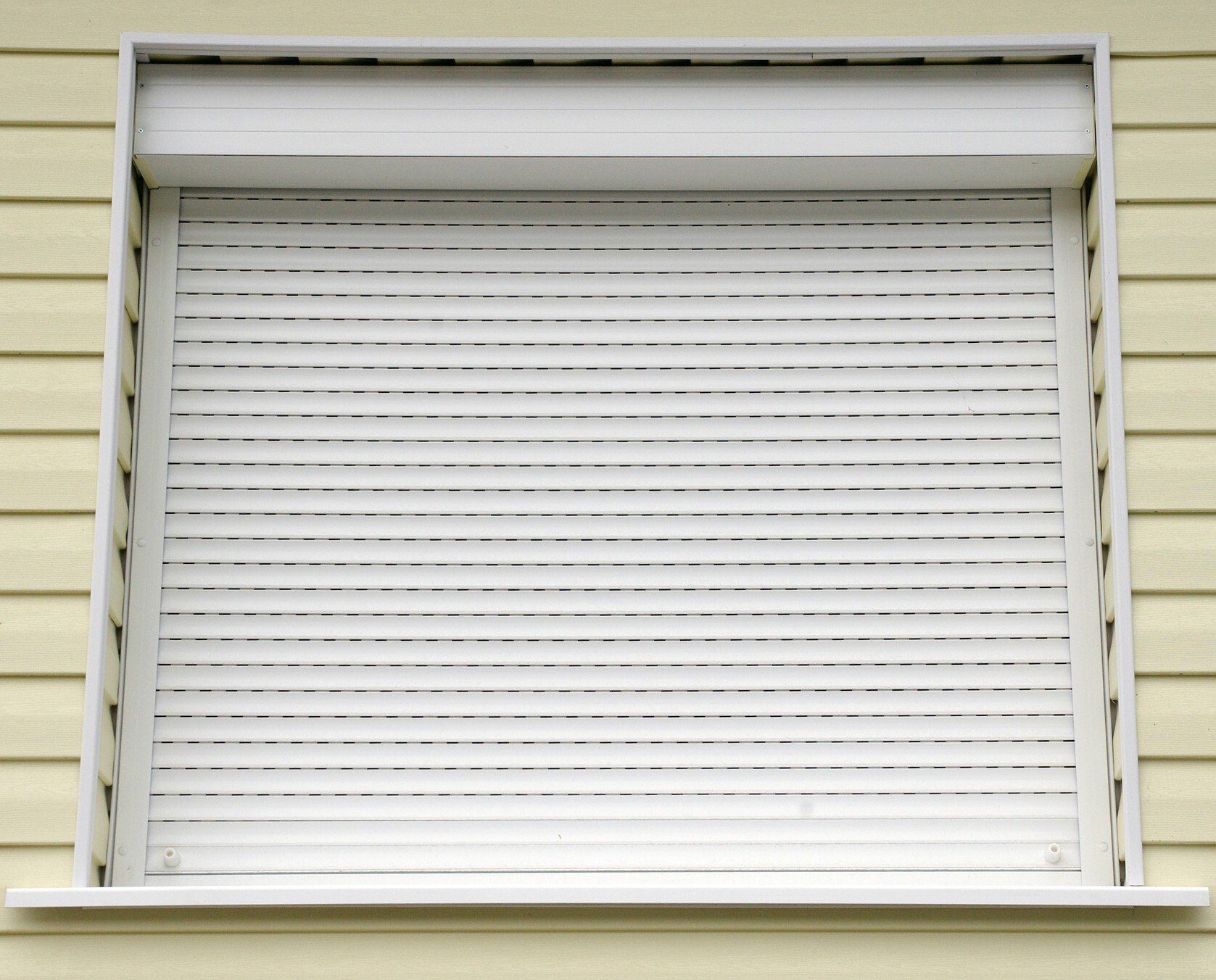 External security roller shutter closed down, set inside of yellow weather boards.