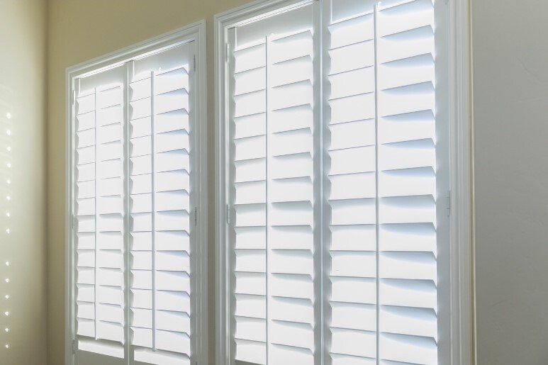 Twin Planation Shutter windows open letting sunshine in, surrounded by yellow walls.