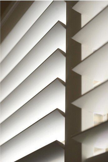Close up of white plantation shutters, opened up fully.