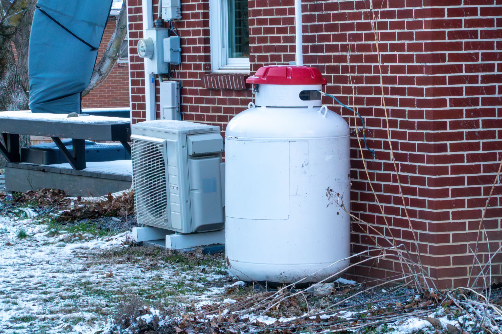 Propane tank and HVAC unit outside brick home in winter for residential heating. Propane tank and HVAC unit outside brick home in winter for residential heating.