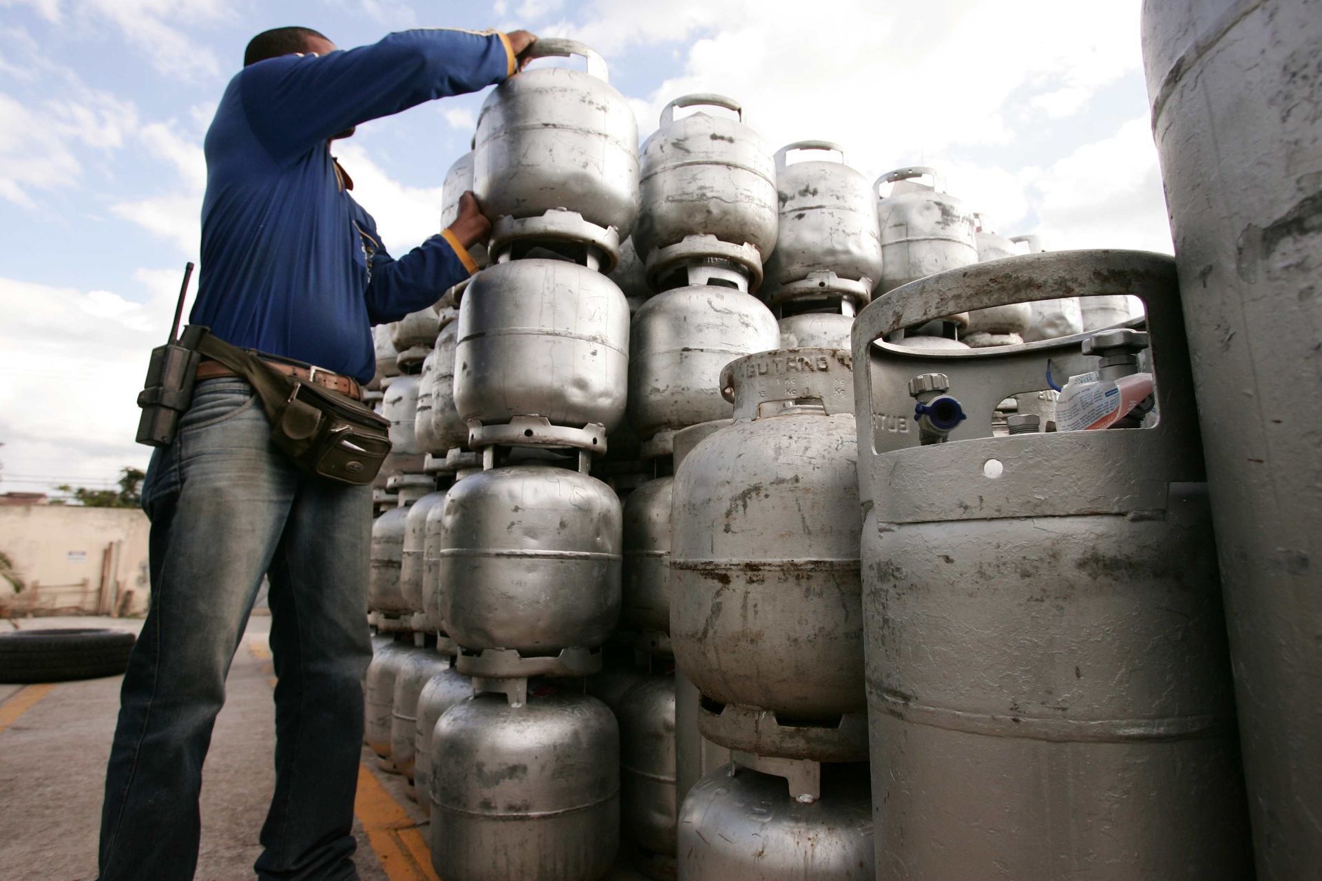 A worker is holding a propane tank to perform a propane delivery A worker is holding a propane tank to perform a propane delivery