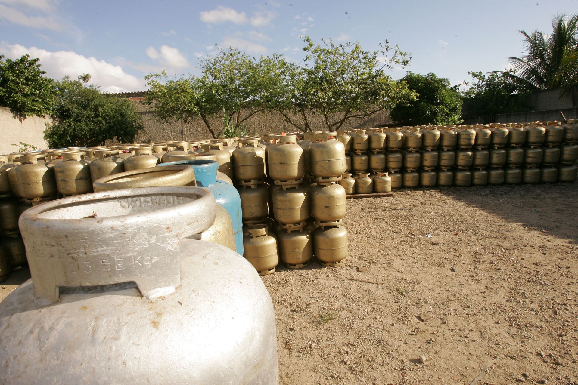 Rows of stacked water jars in a dusty outdoor yard, with a large white container in the foreground