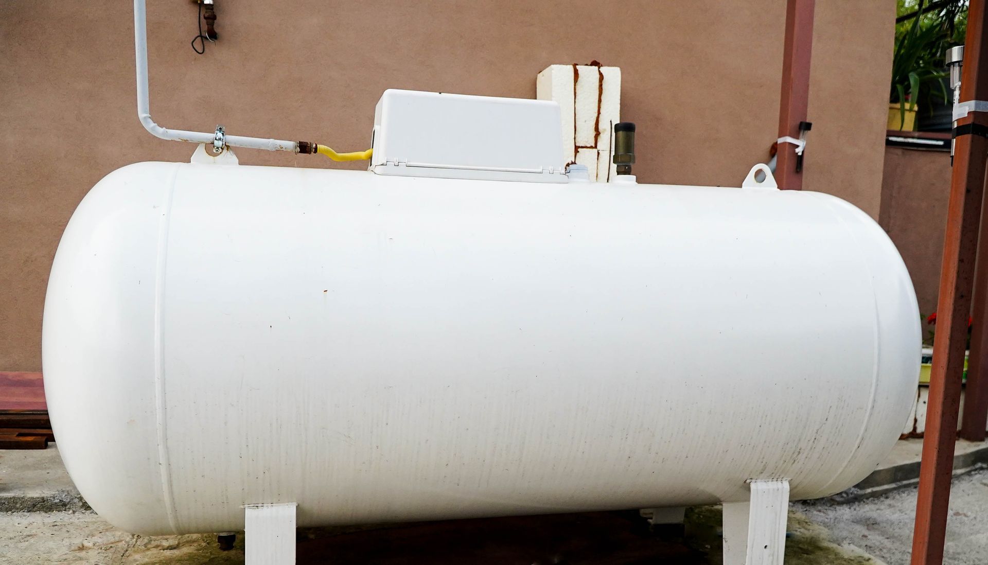 Large white propane storage tank installed outdoors, connected to gas lines supplying.