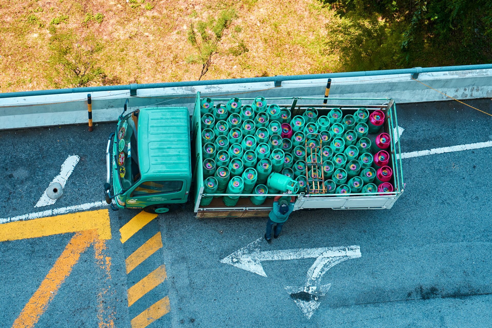 Top-down view of a turquoise truck loaded with green and red produce on a highway shoulder Top-down view of a turquoise truck loaded with green and red produce on a highway shoulder