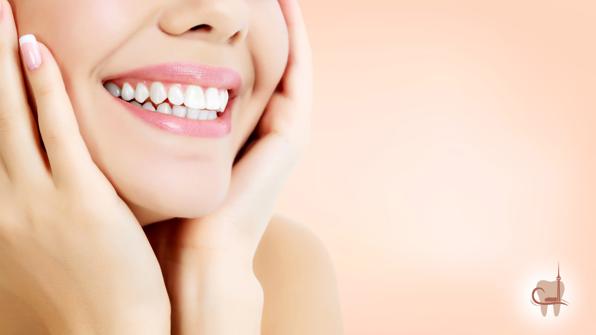 Woman's smiling face, hands framing cheeks; white teeth, pale pink background.