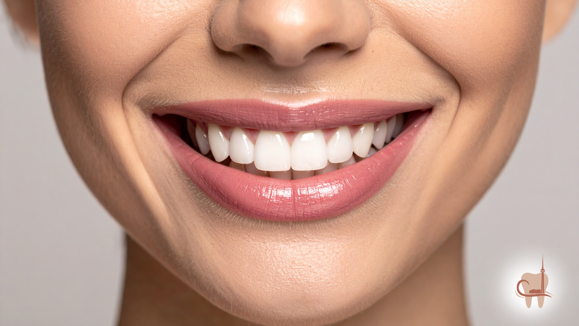 Close-up of a person's mouth, showing slightly discolored teeth and a mole on the chin.