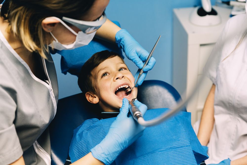 A young boy is getting his teeth examined by a dentist.