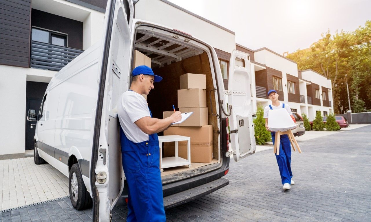 Workers unloading boxes from a delivery van outside an office building