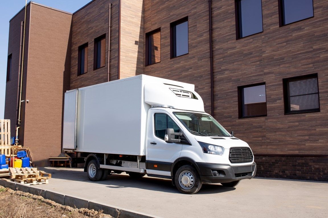White delivery truck parked beside a brick building under construction.