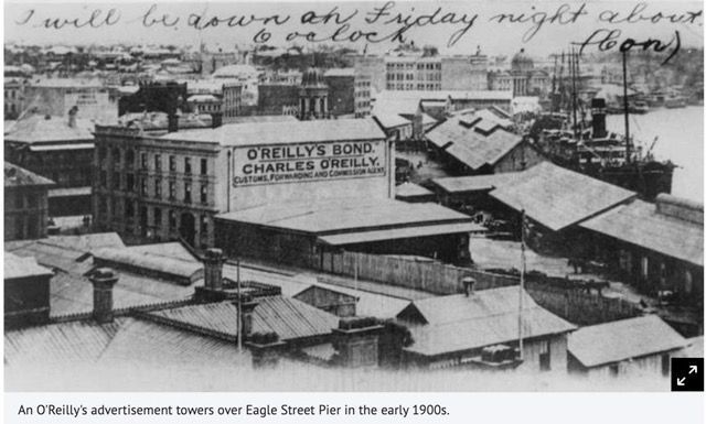 Black and white photo of O'Reilly's advertisement towers over Eagle Street Pier in the early 1900s. 