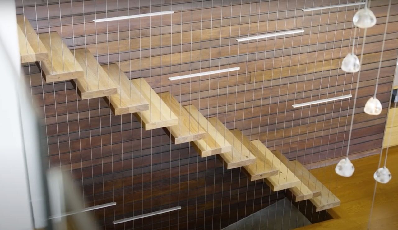 Floating wooden staircase with metal cable supports and modern hanging lights in Brisbane.