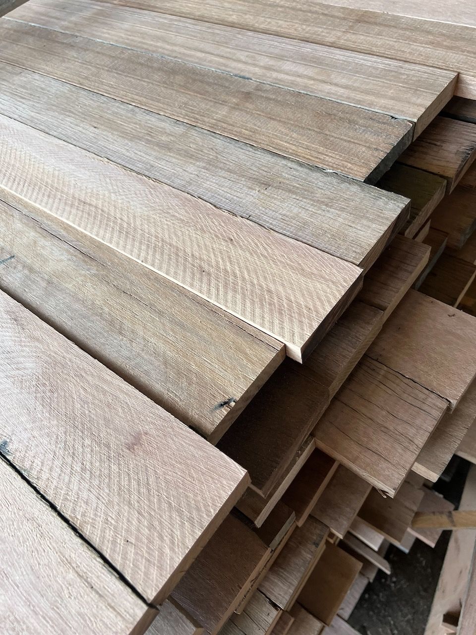 A stack of rough-cut, light brown wooden planks piled neatly on top of each other.