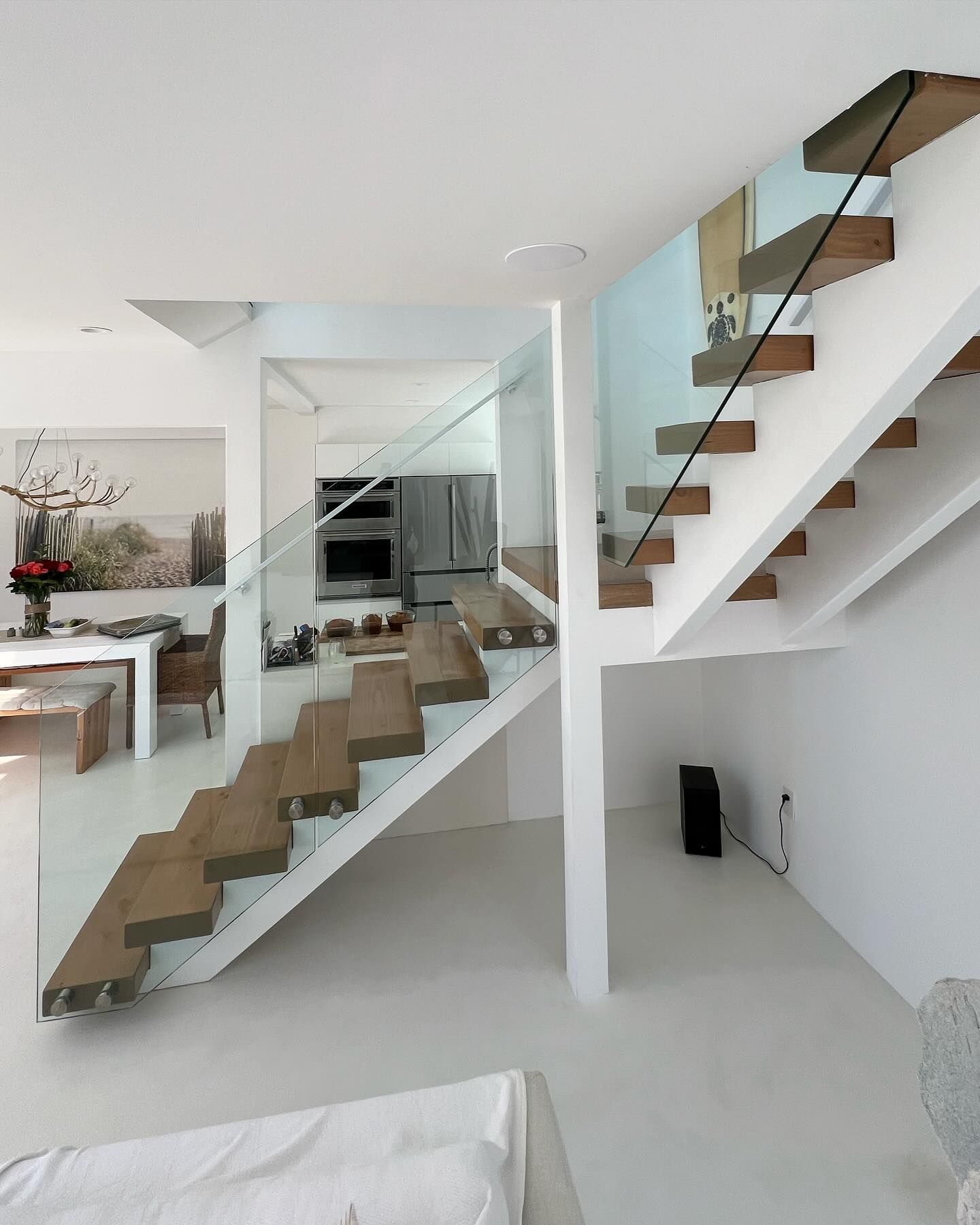 A wooden staircase with a glass railing leading up to the second floor