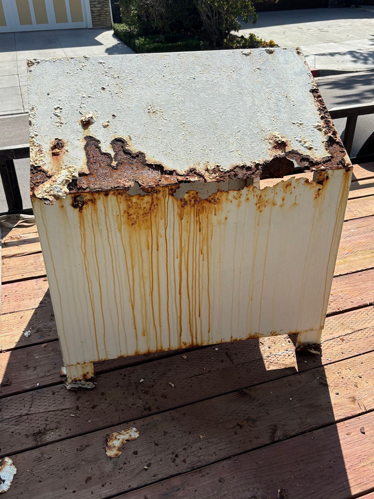A rusty box is sitting on top of a wooden deck.