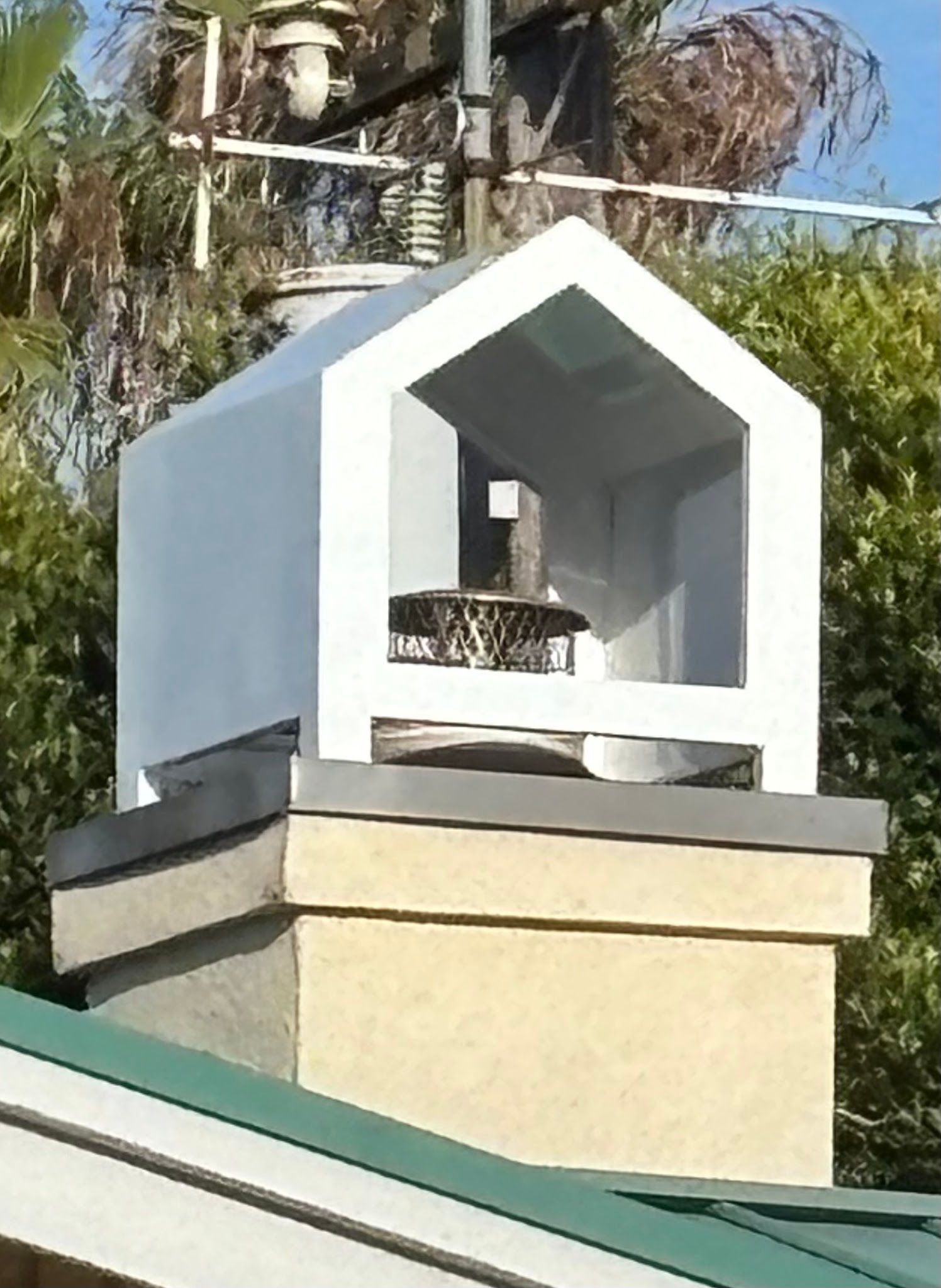 A white birdhouse is sitting on top of a chimney
