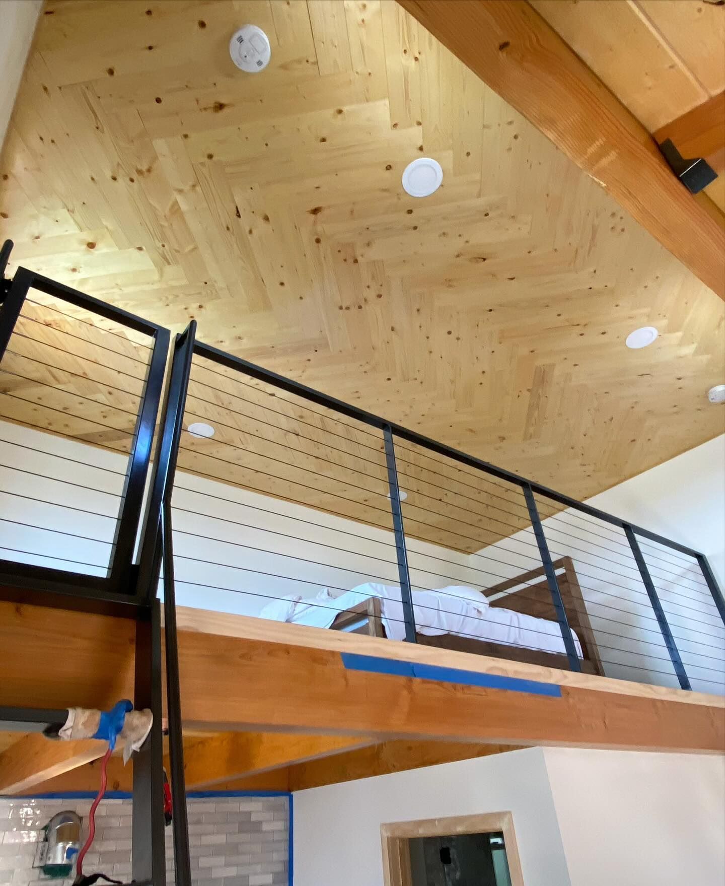 A bedroom with a wooden ceiling and a staircase leading to the second floor.