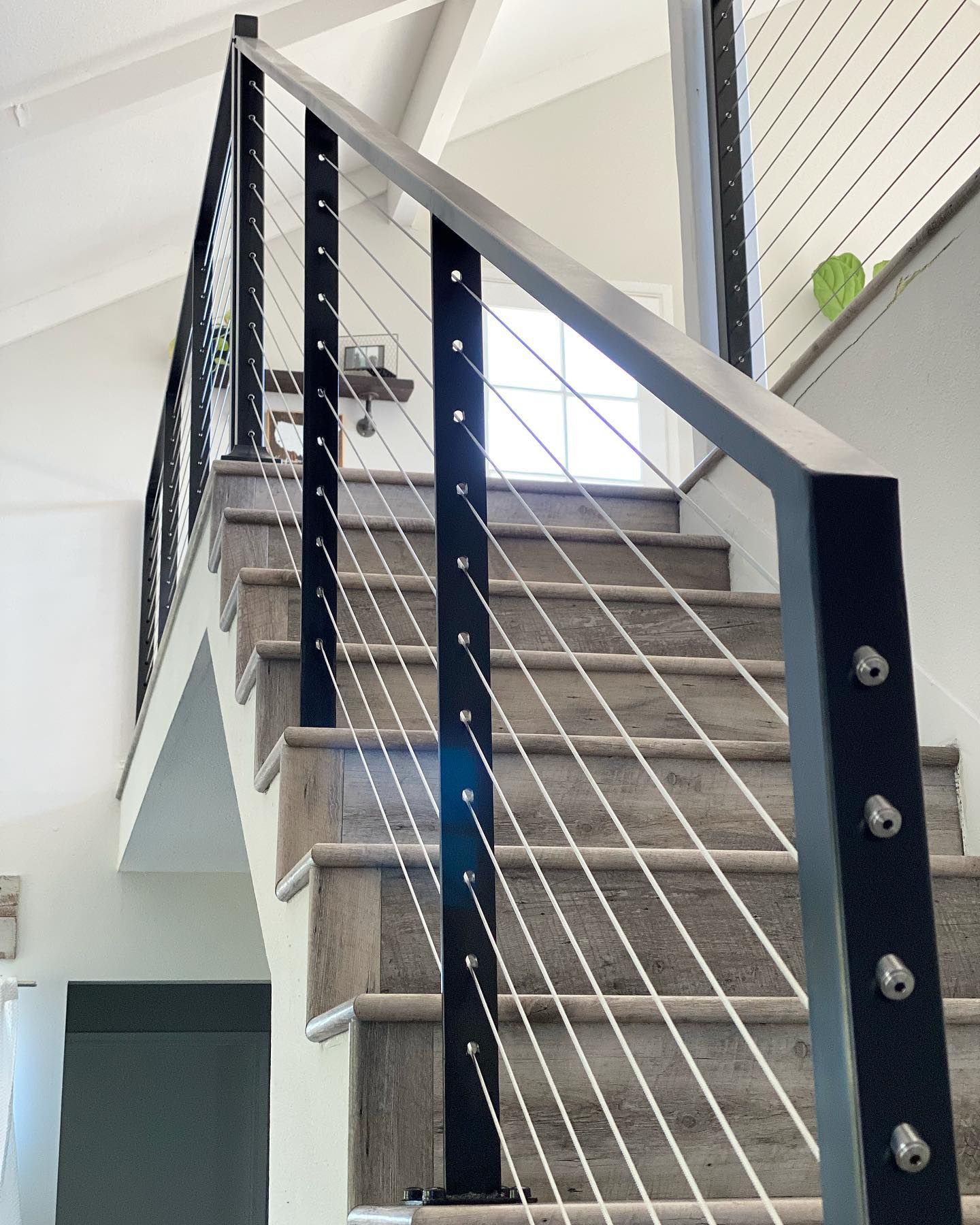 A staircase with a stainless steel railing and wooden steps