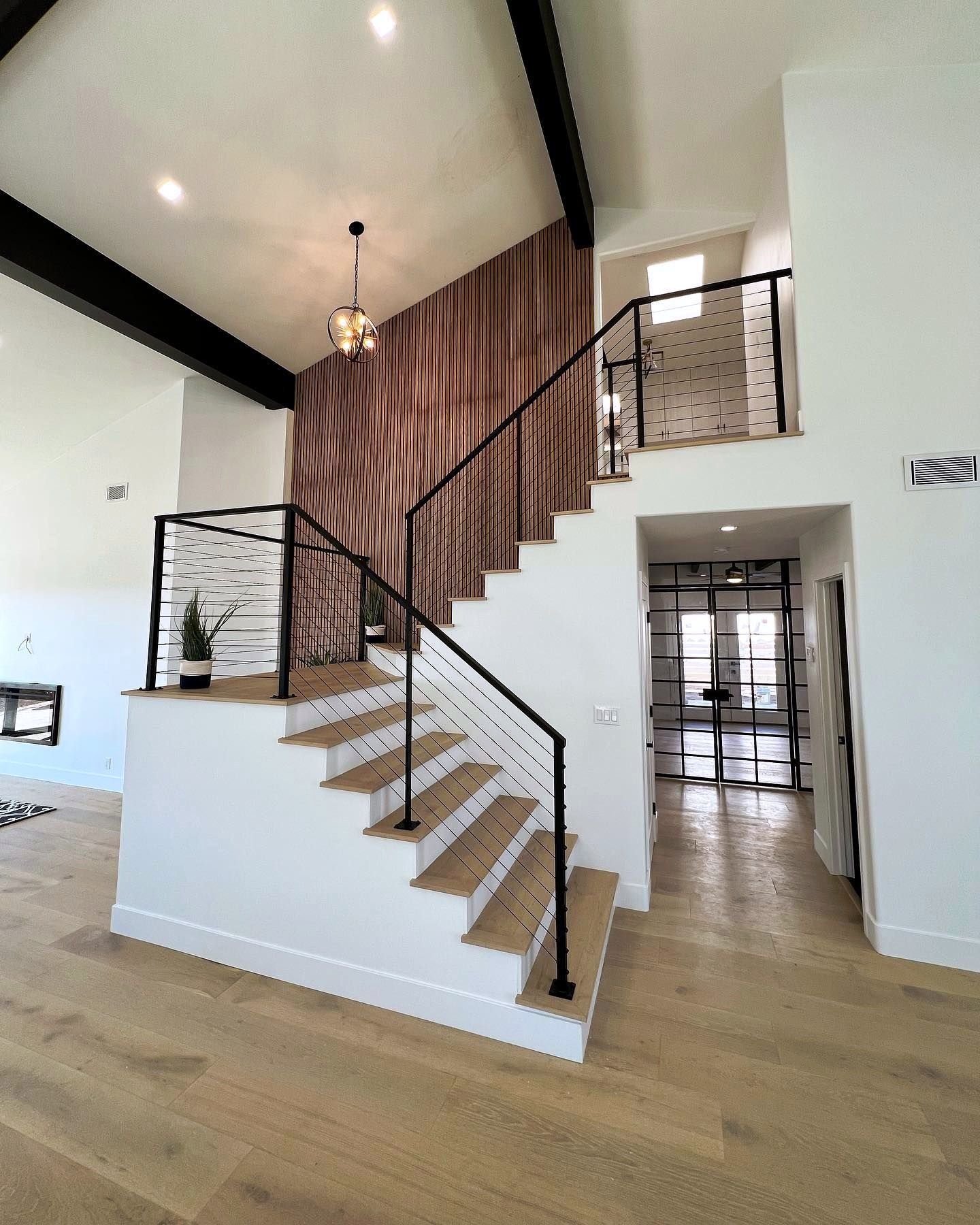 Two-story staircase with black steel and stainless cable railing