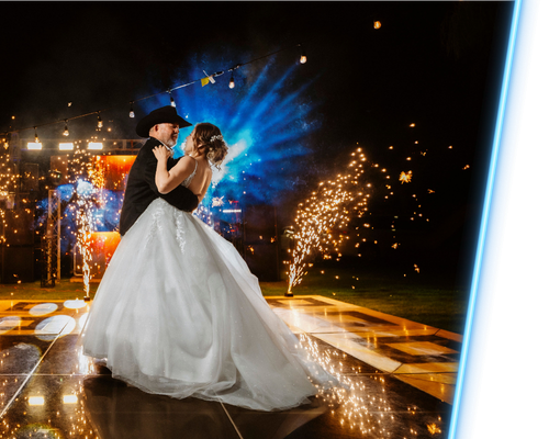 Bride and groom dancing in a sparkler-lit nighttime wedding scene with blue light effects