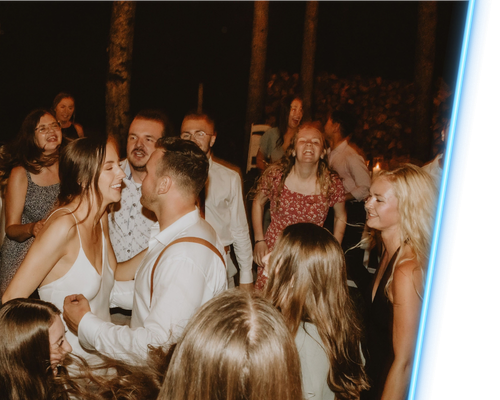 Crowd dancing outdoors at night, with people chatting and smiling under warm lights