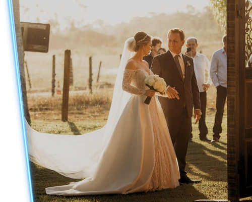 Bride and dad walking outdoors at sunset, bride in a flowing white gown and long veil