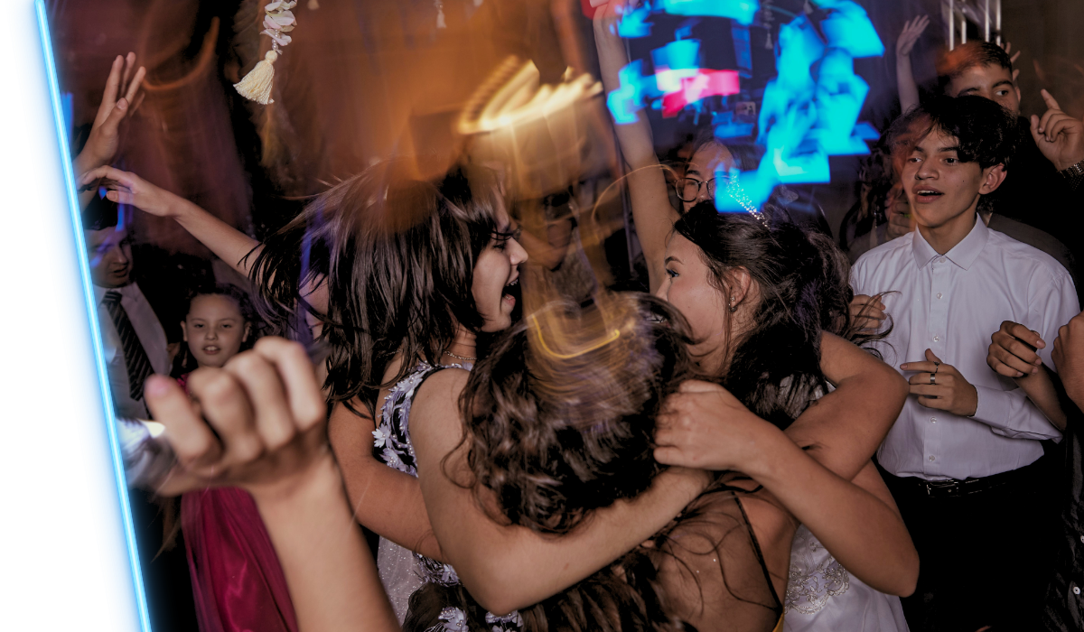 People dancing at a lively party with blue and orange lights, cheering and moving in a crowded scene
