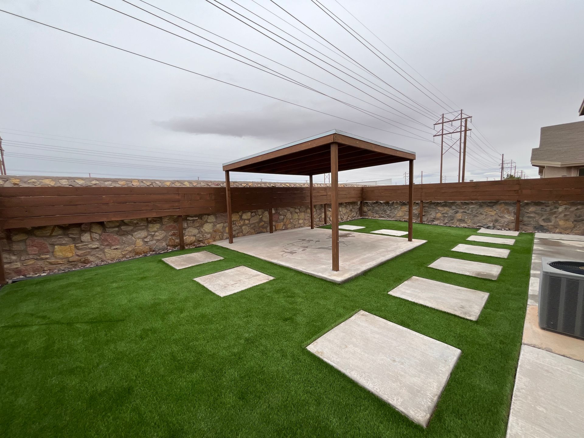 Well-kept green lawn in a fenced backyard with curved stone borders and shrubs Well-kept green lawn in a fenced backyard with curved stone borders and shrubs