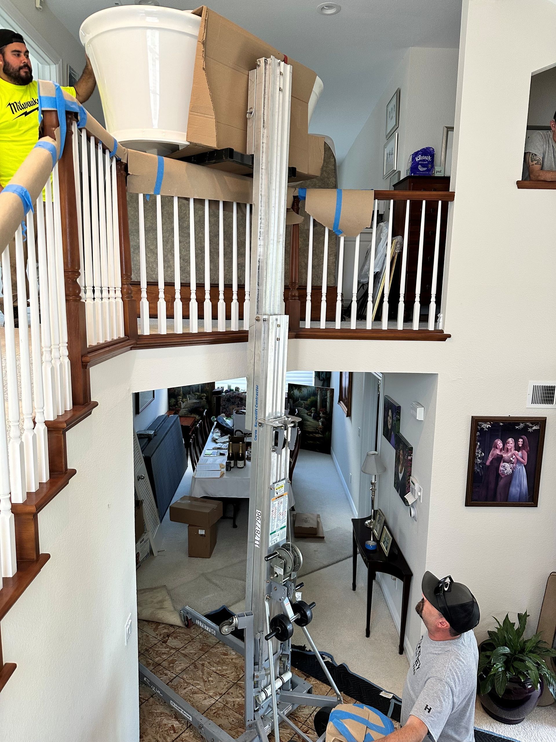 Two-story foyer with collapsed ceiling debris and two people inspecting damage near a ladder