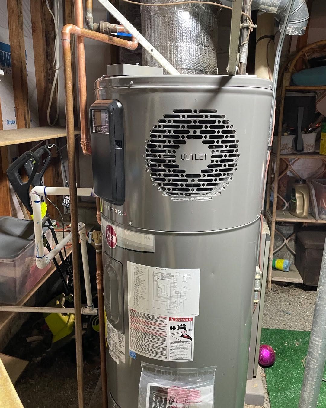 Large silver water heater with vented top, pipes, and labels in a basement utility area