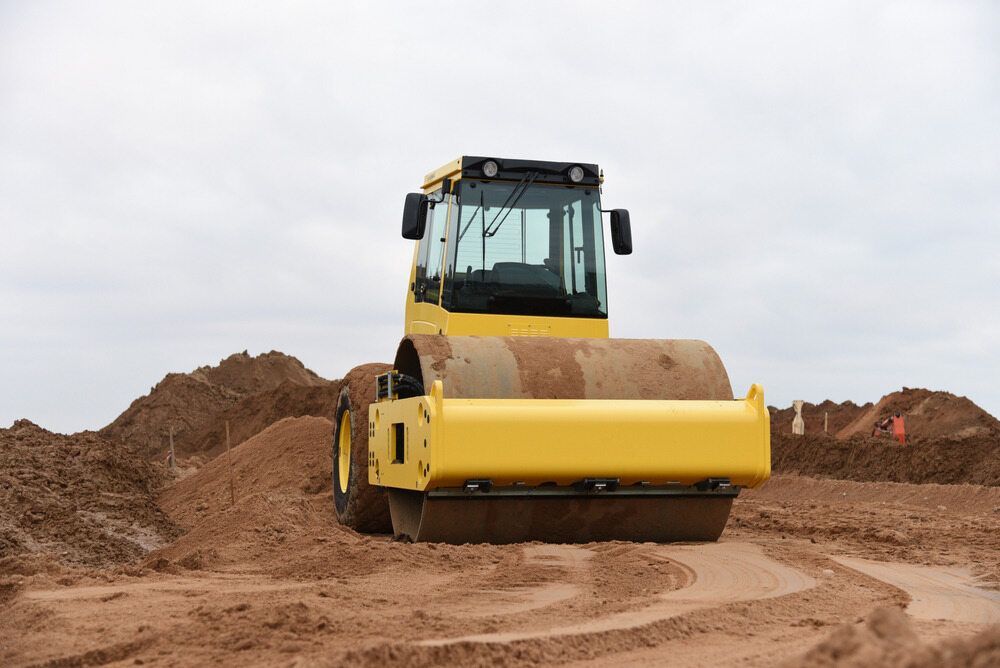 A Yellow Road Roller is Driving on Loose Dirt — North Coast Drilling & Wicks in Bangalow, NSW