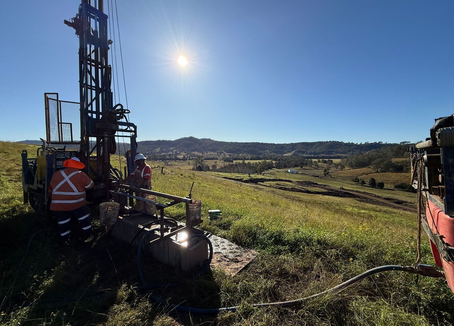 A Tall Machine is standing in Paddock with two workers in uniform — North Coast Drilling & Wicks in Bangalow, NSW