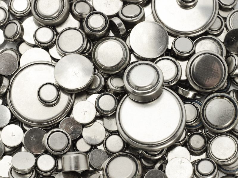Pile of silver button batteries on a white background