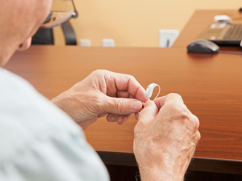 Hands holding a white earbud cable at a wooden table in a meeting room.